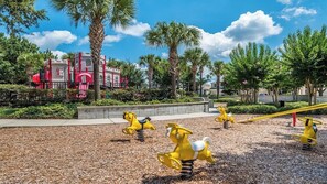A playground with yellow rocking horses and a red building in the background. - Orange Blossom Villa (Kissimmee)