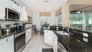 A modern kitchen with white cabinets, a stainless steel microwave, a gas stove, and a granite countertop. - Windsor Hills Resort/2 Miles Disney/Private Pool and Hot Tub/Games Room/FreeWifi (Kissimmee)