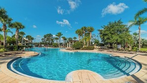 Ein großer Pool im Freien, umgeben von Palmen und Liegestühlen.
