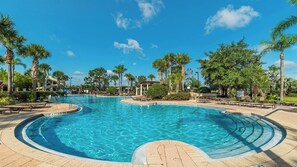 A large outdoor swimming pool surrounded by palm trees and lounge chairs. - Orange Blossom Villa (Kissimmee)