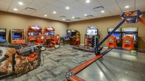 Um quarto com jogos de fliperama, incluindo jogos de corrida e tiro, e uma máquina grande, vermelha e de visual futurista.