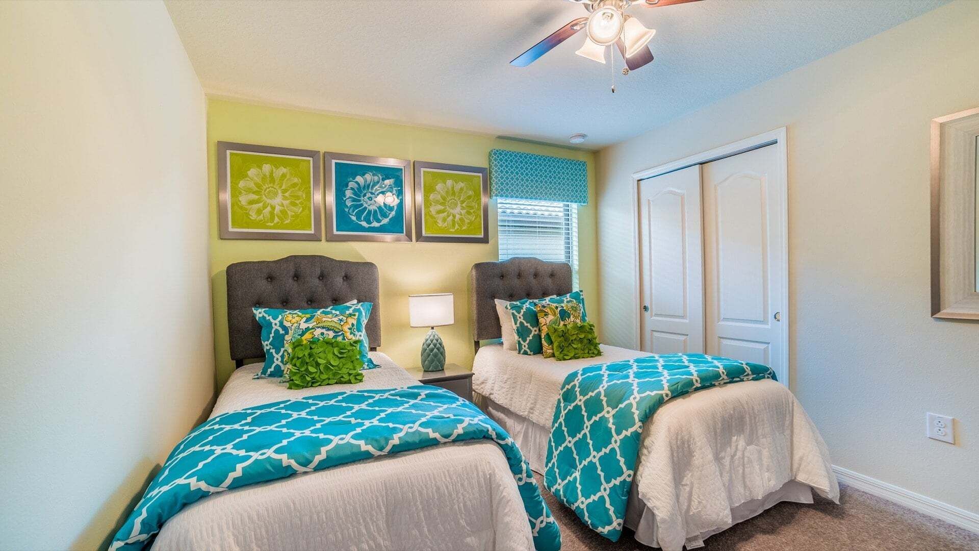 A bedroom with two beds, a ceiling fan, and a door.