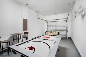 Quarto com mesa de pebolim, duas cadeiras e uma mesa.