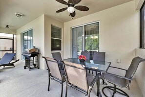 A covered patio area with a glass table, chairs, a ceiling fan, and a grill. - Pooch Parlour - Six Bedroom House, Sleeps 14 (Kissimmee)