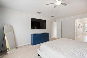 A bedroom with a bed, a dresser, a TV, a ceiling fan, and a door leading to another room. - New Listing! 2 miles Disney/Private pool and spa/water park and resort included! (Kissimmee)