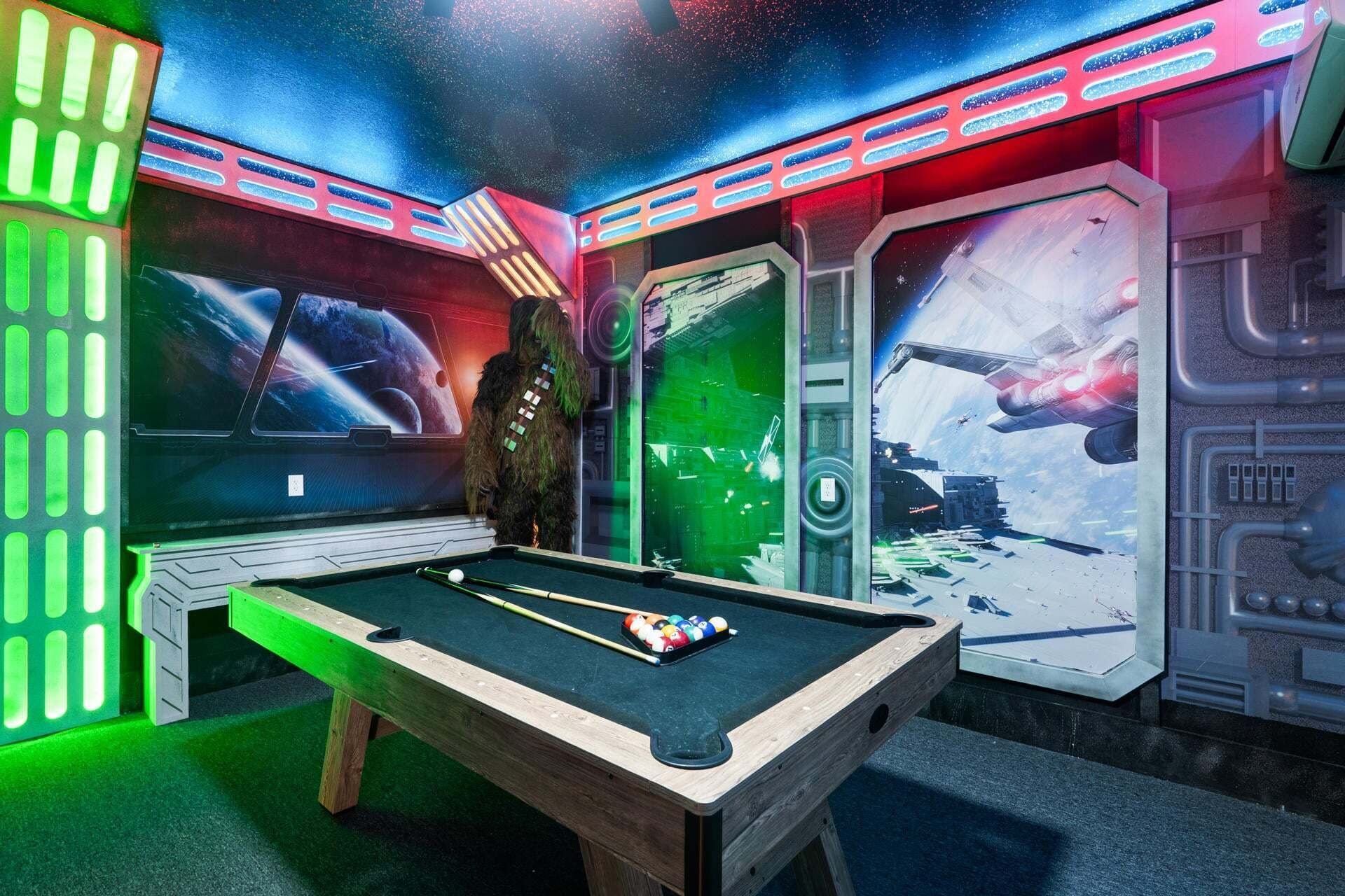 A pool table with a space-themed mural, a plush toy, and a futuristic room design.