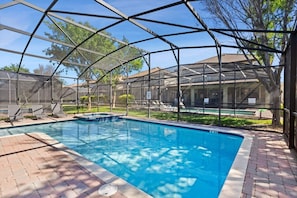A covered swimming pool with a clear view of the surrounding area, including a building with a tiled roof and a grassy lawn. - The Grand Slam - Eight Bedroom Apartment, Sleeps 19 (Kissimmee)