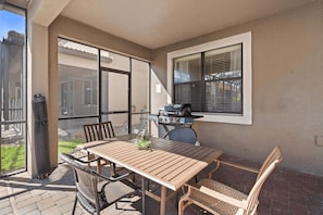 An outdoor patio with a wooden table and chairs, a grill, and a view of a residential area. - The Grand Slam - Eight Bedroom Apartment, Sleeps 19 (Kissimmee)