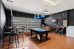 A billiards room with a pool table, chairs, a foosball table, and a ceiling fan. - The Grand Slam - Eight Bedroom Apartment, Sleeps 19 (Kissimmee)