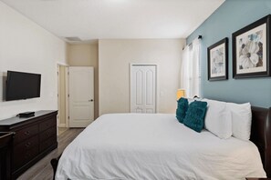 A hotel room with a bed, a television, a dresser, and a door. - The Grand Slam - Eight Bedroom Apartment, Sleeps 19 (Kissimmee)