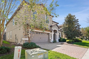 A two-story house with a garage, a driveway, and a well-maintained lawn. - The Grand Slam - Eight Bedroom Apartment, Sleeps 19 (Kissimmee)