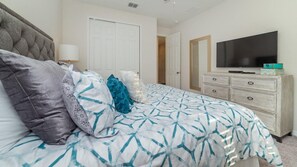 A bedroom with a bed, a dresser, a television, and a door. - The Forever Home - Five Bedroom House, Sleeps 12 (Kissimmee)