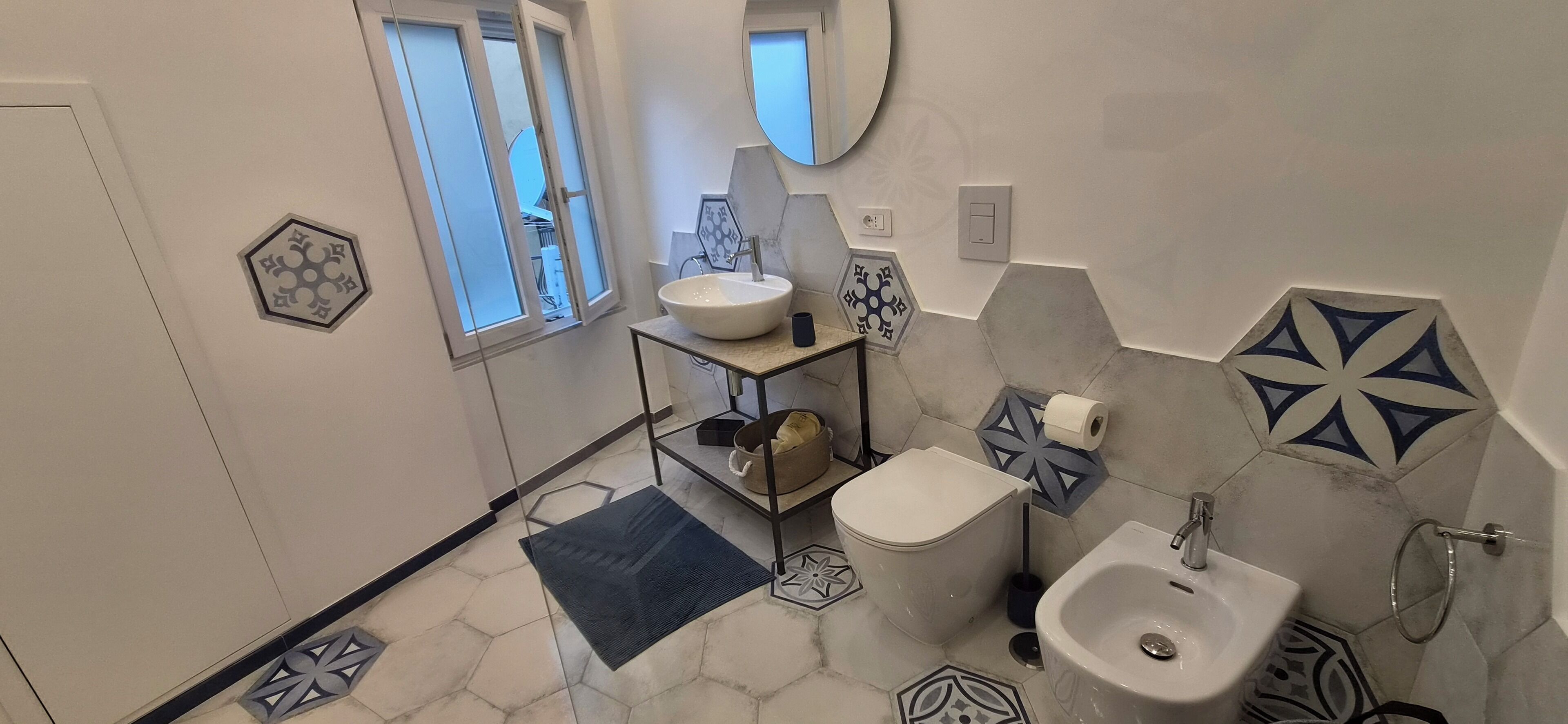 Un baño con lavamanos blanco, un bidé, un inodoro y un espejo.