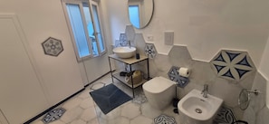Une salle de bain avec un lavabo blanc, un bidet, des toilettes et un miroir.