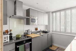 A modern kitchen with a built-in oven, microwave, and a large window with blinds. - The Bee Apartment & Patio, St John's Mews, 10-Minutes Walk From The York Minster (York)