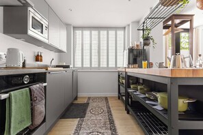 A modern kitchen with a built-in oven, microwave, and a window with blinds. - The Bee Apartment & Patio, St John's Mews, 10-Minutes Walk From The York Minster (York)