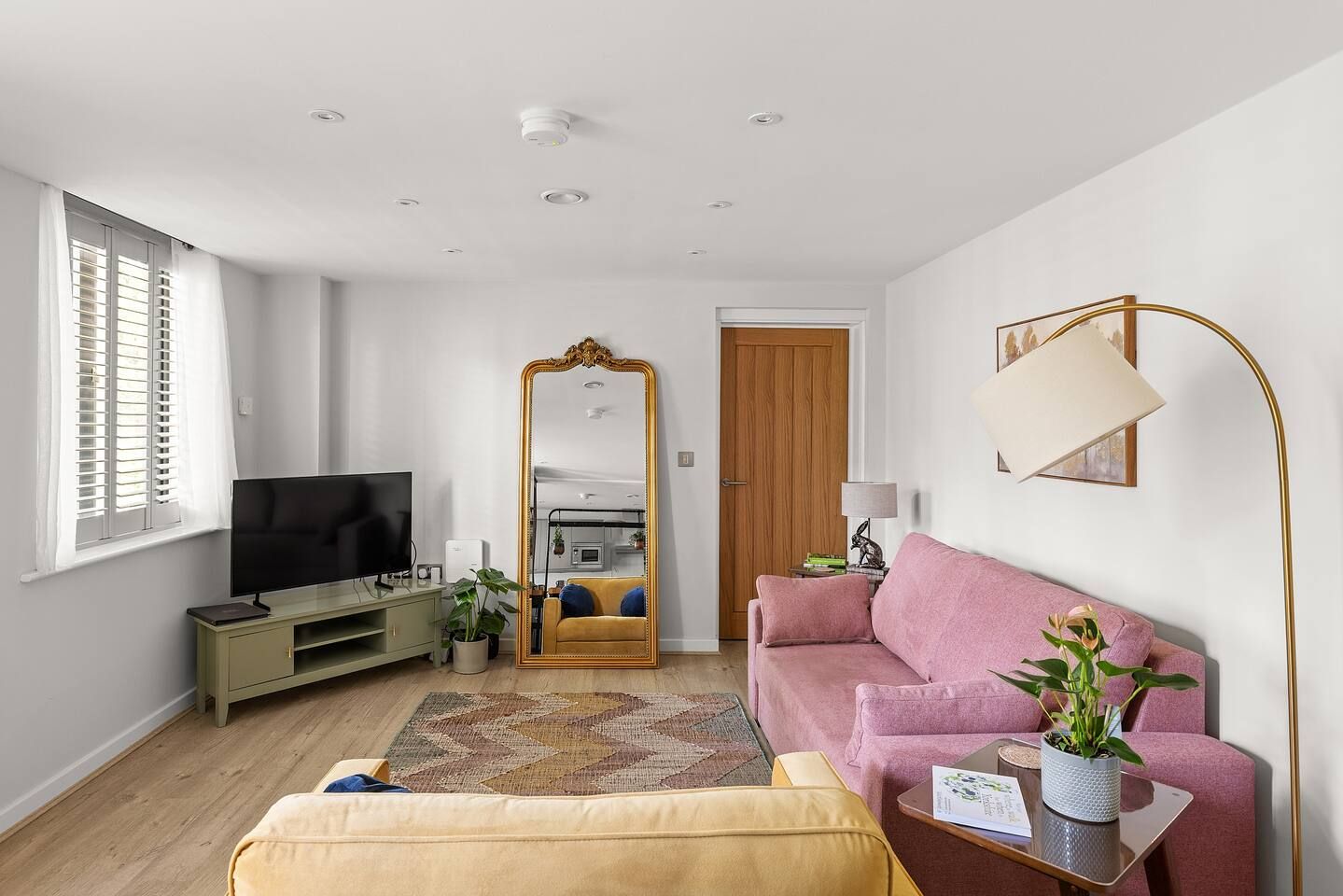 A modern living room with a television, sofa, and a large mirror.