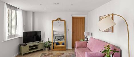 A modern living room with a television, sofa, and a large mirror.