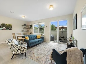 A living room with a sofa, patterned armchair, and a coffee table. - Snowbird Special: Mint 3BR Gated Townhome, Seasonal Stay Available (Stuart)