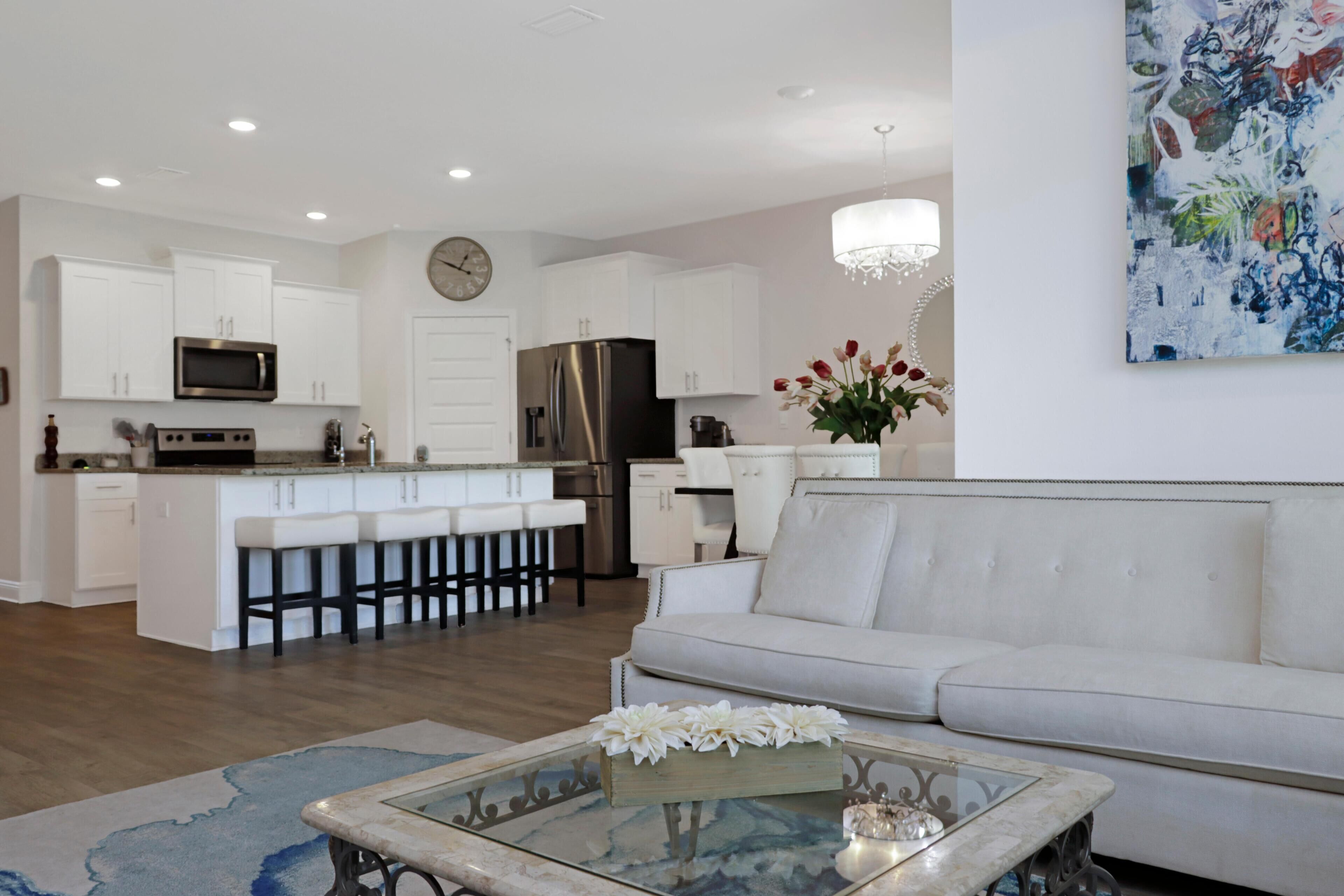 A modern kitchen with white cabinets, stainless steel appliances, and a central island with bar stools.