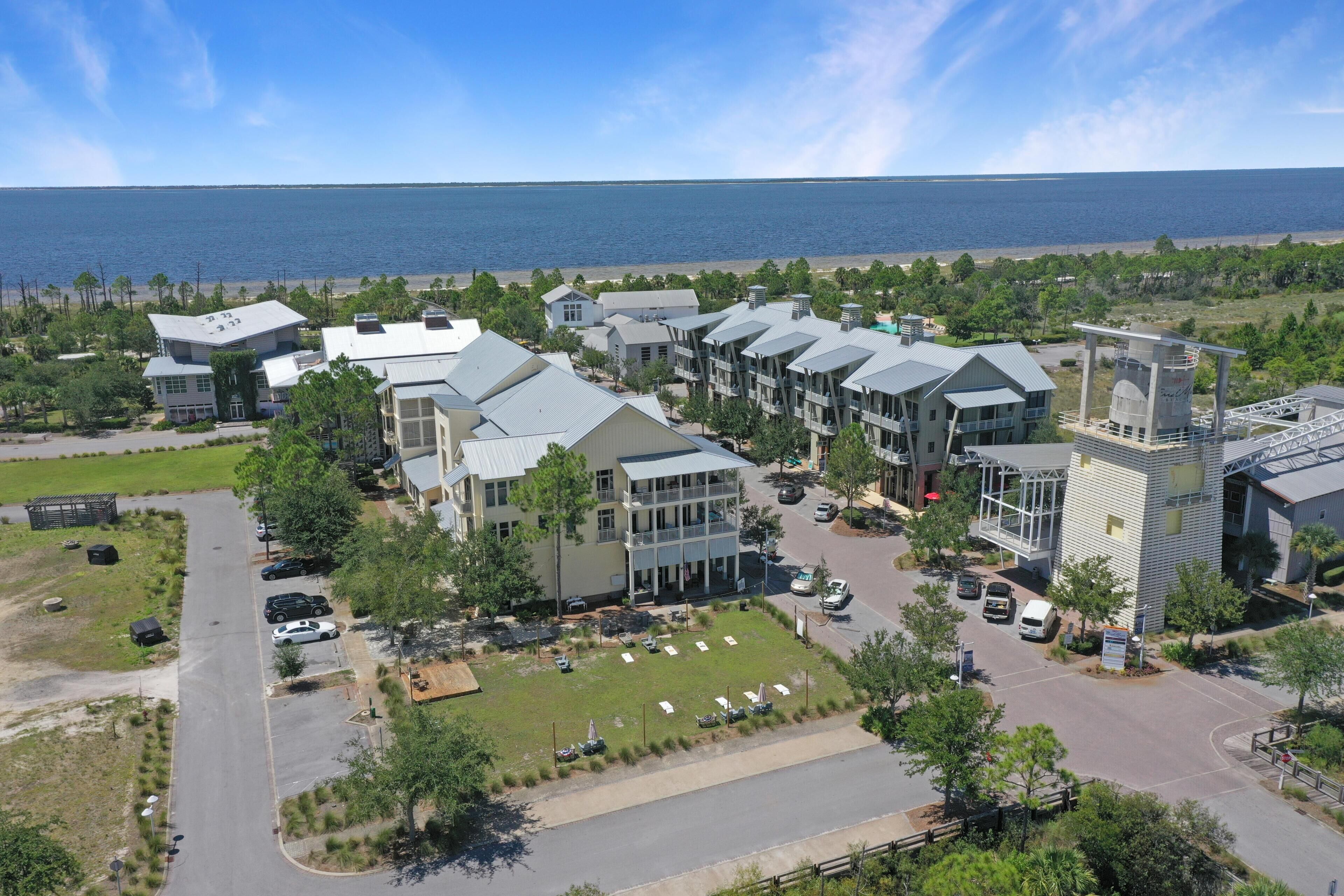 A coastal hotel with multiple buildings, a parking area, and a view of the ocean.