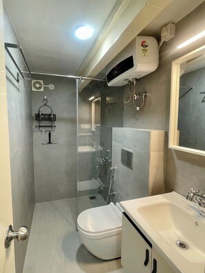 Een kleine badkamer met toilet, wastafel en douche.