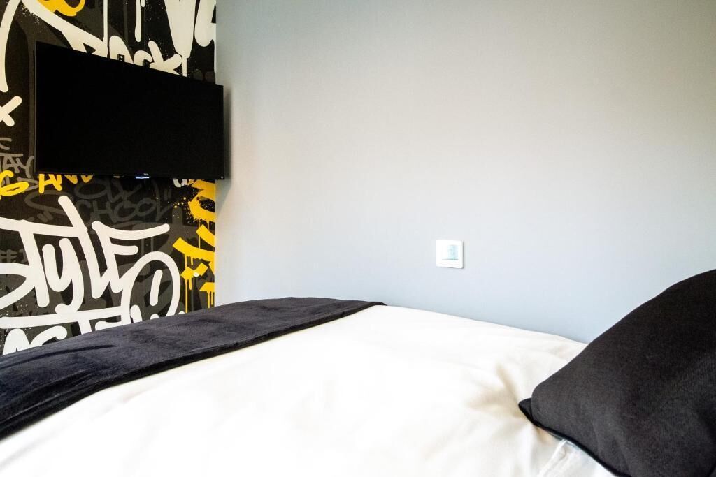 A bed with a black headboard and a white mattress, a black blanket, and a black pillow.