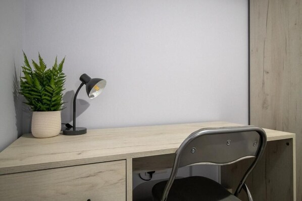 Un espacio de trabajo con escritorio, silla, planta en maceta y lámpara de escritorio.