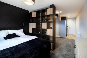A modern bedroom with a large bed, a built-in wardrobe, and a separate bathroom.