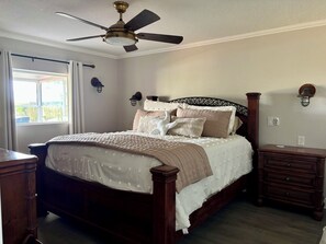 Ein Schlafzimmer mit einem Bett, Deckenventilator, Nachttischlampen und einem Nachttisch.