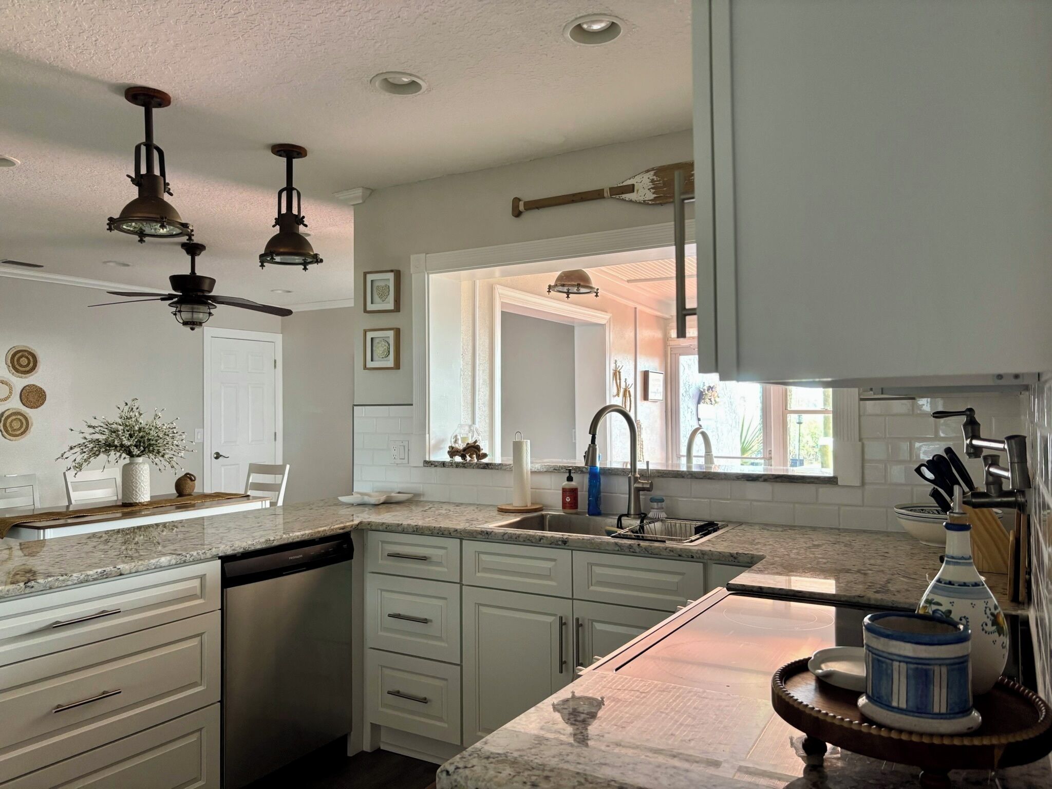 A kitchen with white cabinetry, a dishwasher, a sink, and a countertop with a vase and a knife block.