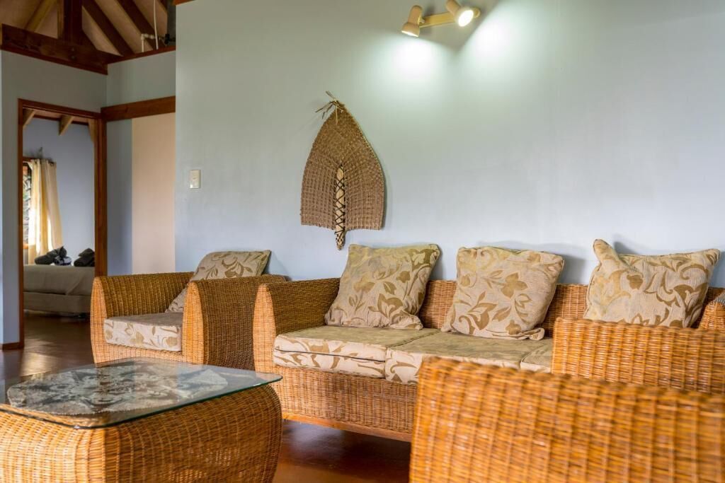 A room with a wicker sofa set, a glass coffee table, and a wall-mounted decorative item.
