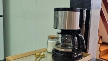 Eine Kaffeemaschine auf einem Holztablett mit einer Marmarausziehtafel, ein Zuckerbehälter und zwei goldene Löffel.