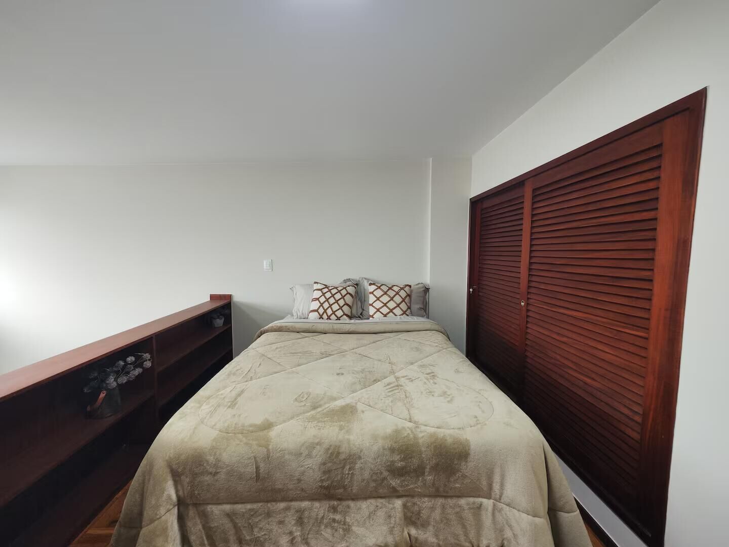 Une chambre à coucher avec un lit, une étagère en bois et une armoire en bois.