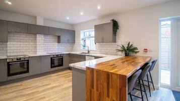 A modern kitchen with grey cabinets, a wooden island, and a built-in oven.