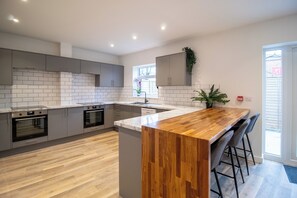 A modern kitchen with grey cabinets, a wooden island, and a built-in oven. - 29 Twyford (Eastleigh)