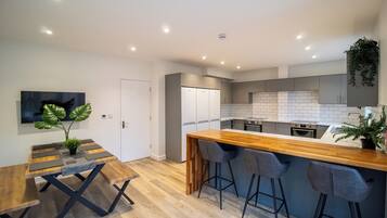 A modern kitchen with a wooden island, bar stools, and a dining table with a unique design.