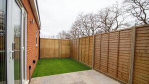 A backyard with a green lawn, a wooden fence, and a brick wall. - 29 Twyford (Eastleigh)