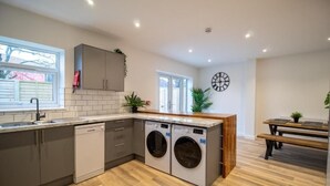 A modern kitchen with built-in appliances, a wooden dining table, and a bench. - 29 Twyford (Eastleigh)