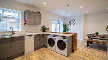 A modern kitchen with built-in appliances, a wooden dining table, and a bench.