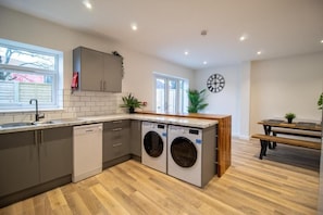 A modern kitchen with built-in appliances, a wooden dining table, and a bench.