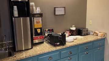 Una cocina con una cafetera, un dispensador de masa para gofres y un tostador sobre la encimera.