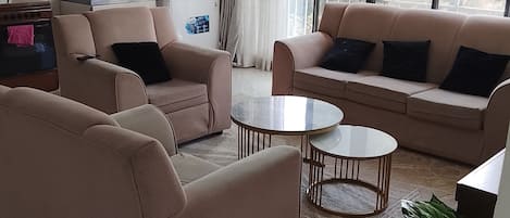 A modern living room with a sofa set, a coffee table, and a dining area.