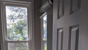 Une salle de bain avec une fenêtre, un lavabo et une porte.