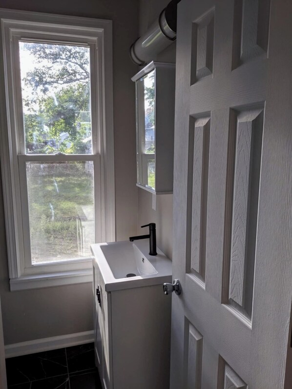 A bathroom with a window, a sink, and a door.