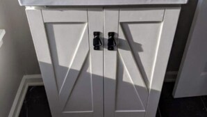 Une salle de bain avec un lavabo blanc, un robinet noir et des meubles de rangement.