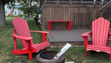 Eine Terrasse mit roten Adirondack-Stühlen, einem Feuerkorb und einer kanadischen Flagge.