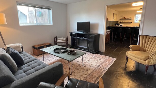 Una sala de estar con un sofá, una mesa de centro, una televisión y una cocina al fondo.