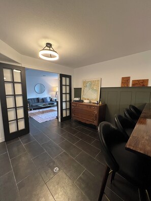 A modern living room with a dining area, a large mirror, and a map on the wall.