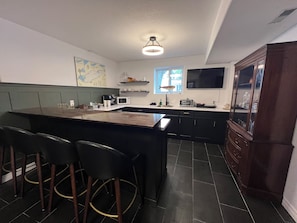 Una cocina con barra, muebles oscuros, un mapa en la pared y una ventana con vistas.